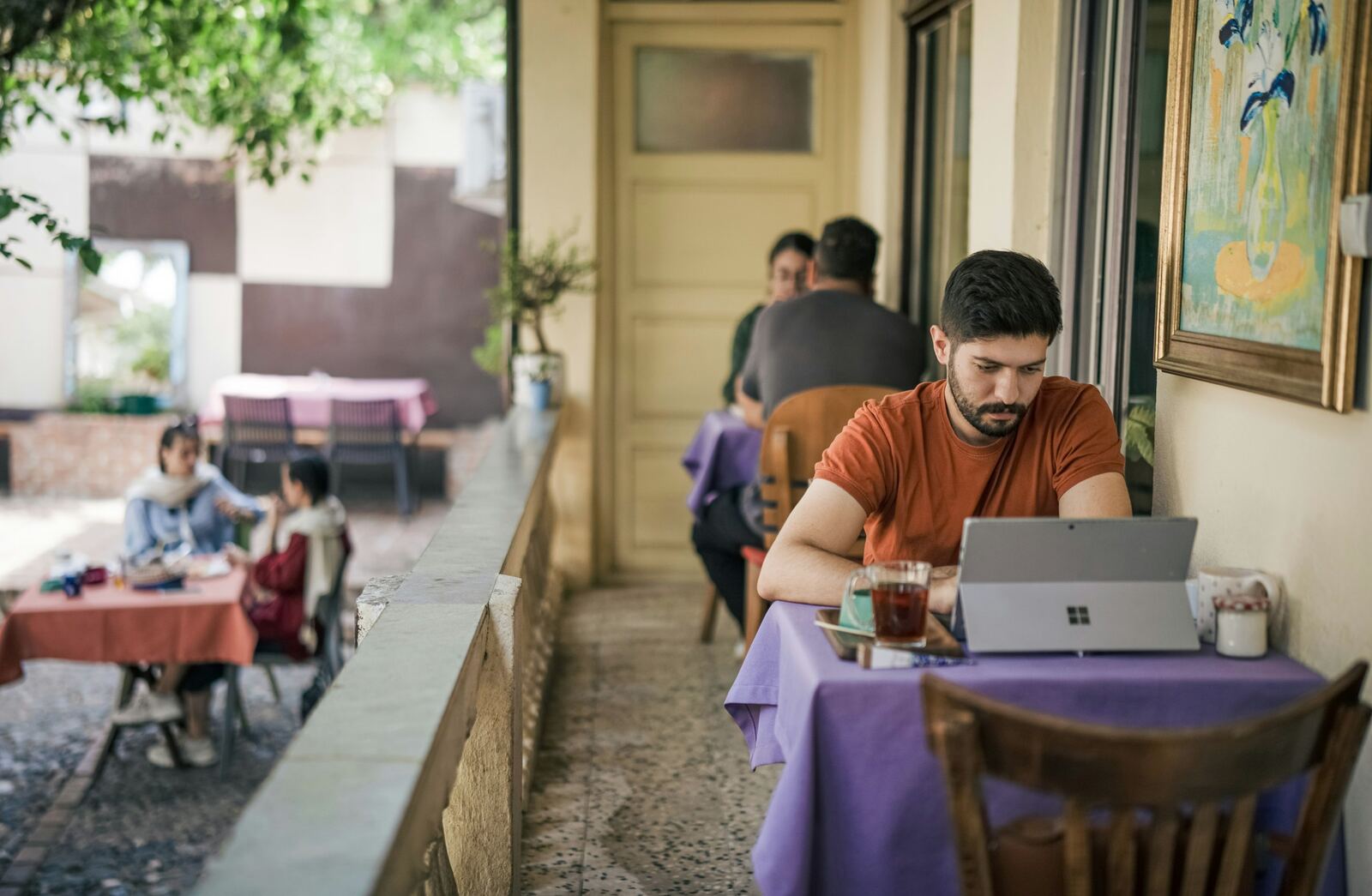 Inhaber am Laptop auf der Terrasse eines Cafés